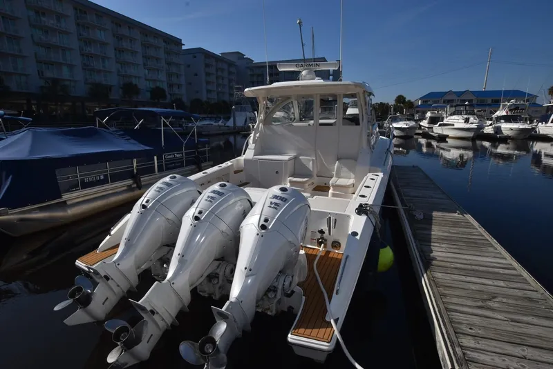 Slide: The Image of 2022 Pursuit OS 355 Offshore boat docked with triple outboard engines. - 2