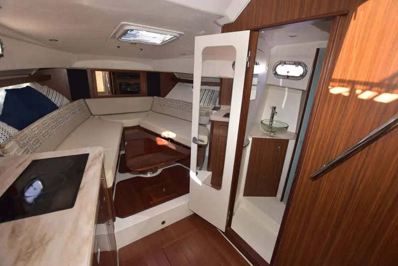 Slide: The Image of 2022 Pursuit OS 355 Offshore cabin interior with seating, kitchenette, and bathroom. - 20
