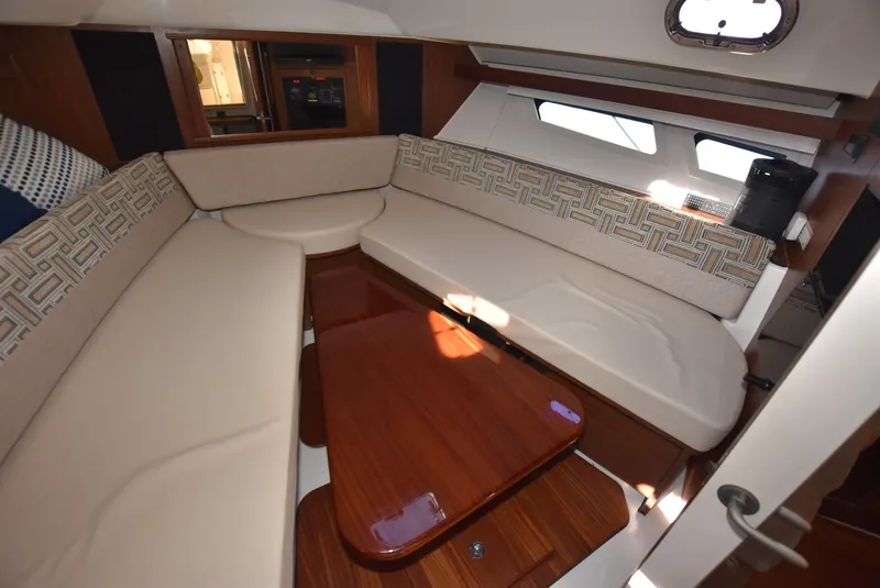 Slide: The Image of 2022 Pursuit OS 355 Offshore cabin with beige seating and wooden table. - 22
