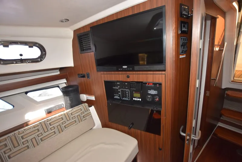 Slide: The Image of 2022 Pursuit OS 355 Offshore cabin interior with TV, control panel, and seating area. - 23