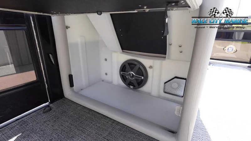 Slide: The Image of 2025 Barletta X23U boat interior storage compartment with speaker and carpeted flooring. - 23
