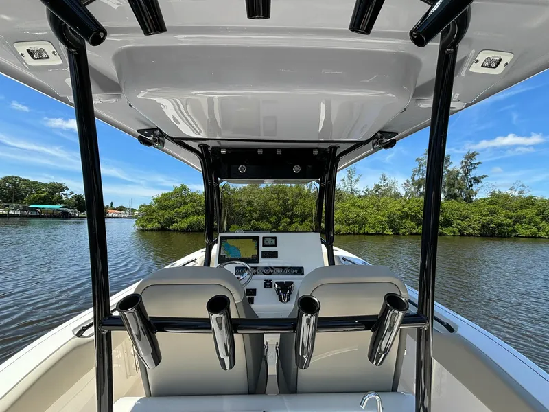 Slide: The Image of 2025 Key West 263 FS boat interior with dual seats and control panel on a calm river. - 10