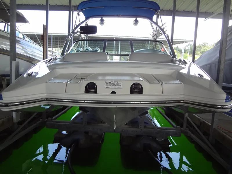 Slide: The Image of 2004 MasterCraft X-Star boat docked, rear view with blue canopy and green water reflection. - 2