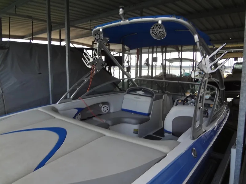 Slide: The Image of 2004 MasterCraft X-Star boat with blue and gray interior, docked under a covered marina. - 8