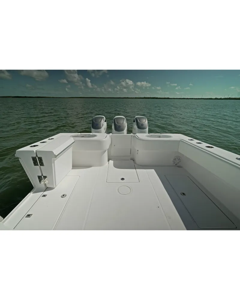 Slide: The Image of 2018 SeaHunter 39 Tournament boat on calm water, featuring spacious deck and triple engines. - 17
