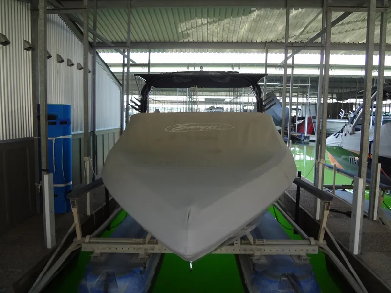 Slide: The Image of 2022 Sanger V237 S boat covered in storage at a marina. - 52