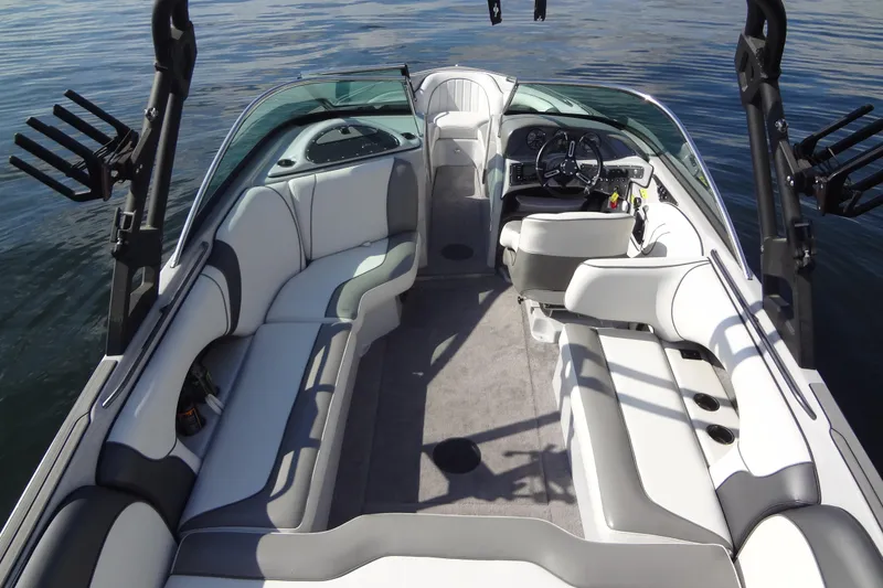 Slide: The Image of 2022 Sanger V237 S boat interior with sleek seating and modern dashboard on calm water. - 9