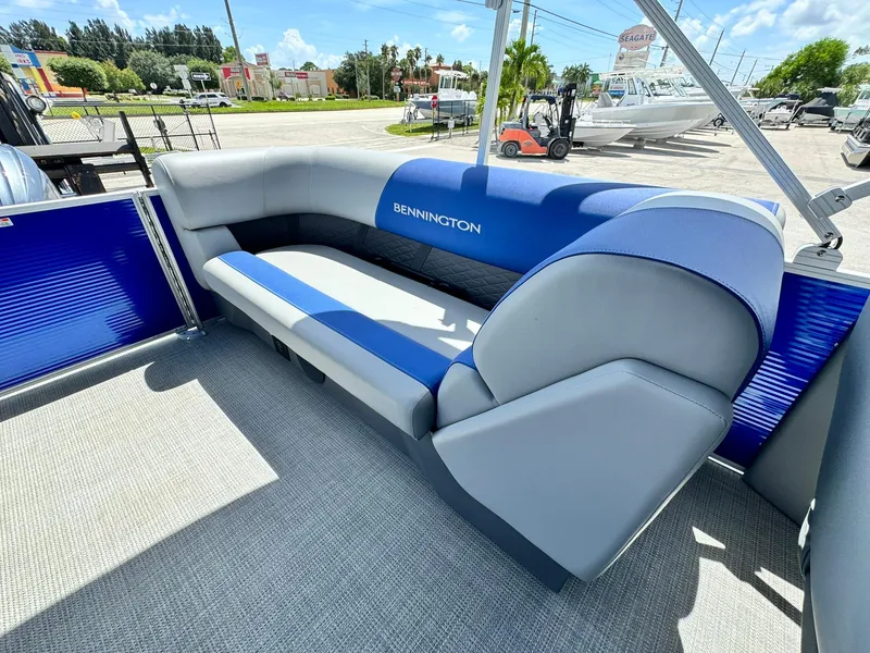 Slide: The Image of 2024 Bennington 22 SSR-SPS pontoon boat with blue and gray seating under sunny skies. - 11