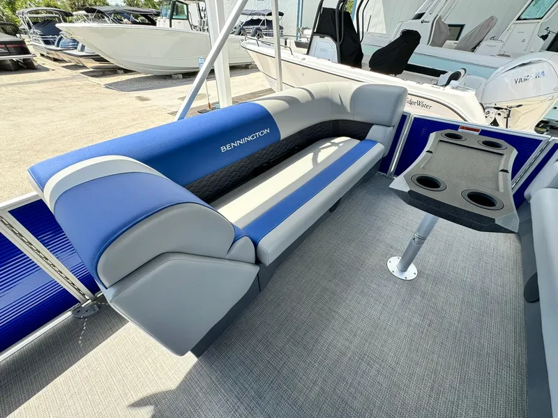 Slide: The Image of 2024 Bennington 22 SSR-SPS pontoon boat interior with blue and gray seating and table. - 21