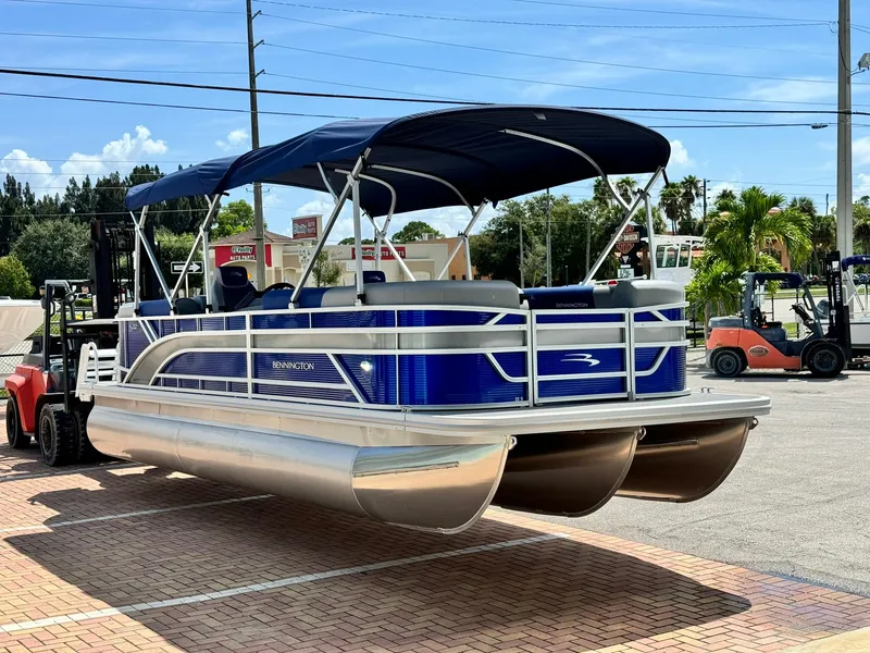 Slide: The Image of 2024 Bennington 22 SSR-SPS pontoon boat with blue canopy on display outdoors. - 3
