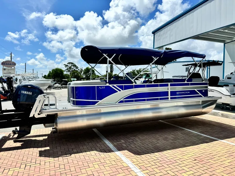 Slide: The Image of 2024 Bennington 22 SSR-SPS pontoon boat with blue canopy, parked outdoors. - 4