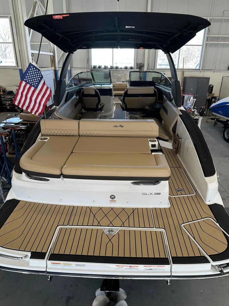 Slide: The Image of 2025 Sea Ray 280SLX boat with tan seating and American flag in a showroom. - 3