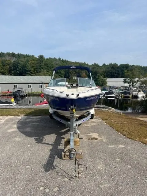 Slide: The Image of 2005 Monterey 194 FS boat on trailer, parked near marina with trees in background. - 3