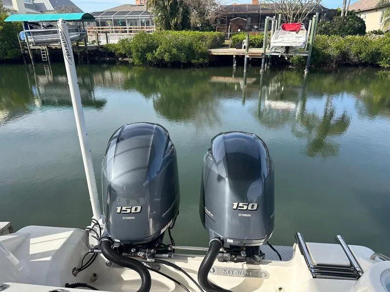 Slide: The Image of 2019 Key West 244 Center Console with twin 150 Yamaha engines docked by a serene canal. - 19
