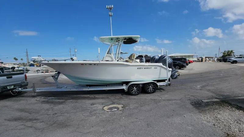 Slide: The Image of 2019 Key West 244 Center Console boat on trailer in parking lot under blue sky. - 2