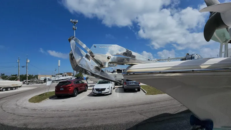 Slide: The Image of 2019 Key West 244 Center Console boat with anchor, parked near cars under a blue sky. - 49