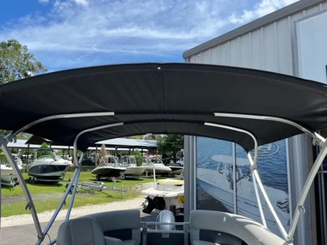 Slide: The Image of 2023 SunChaser Vista 18 Fish boat with canopy, parked near a marina. - 12