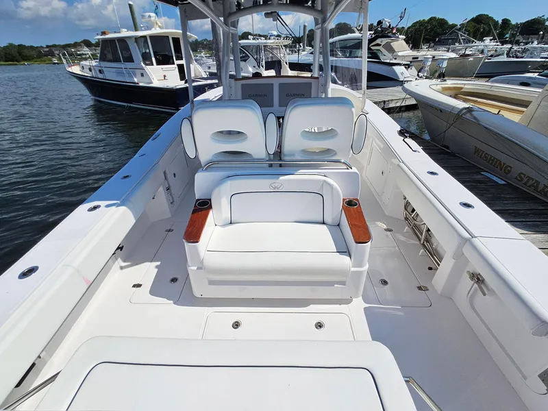 Slide: The Image of 2022 Southport 30 FE boat interior with white seating and wooden accents, docked at a marina. - 7