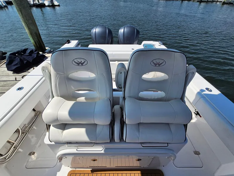 Slide: The Image of 2022 Southport 30 FE boat seats with dual engines, docked by the water. - 8