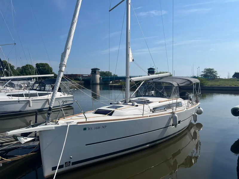 Slide: The Image of 2021 Dufour 360 sailboat docked in a serene marina setting. - 0