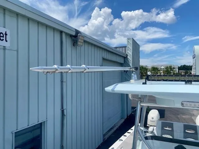 Slide: The Image of 2020 Twin Vee 240 CC boat with outriggers, docked beside a metal building under a blue sky. - 15