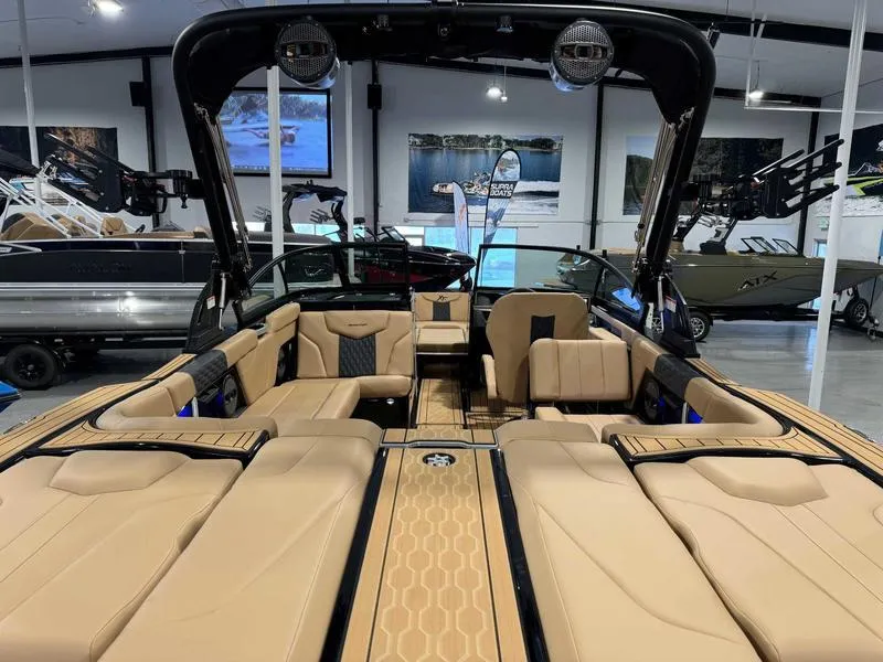 Slide: The Image of 2025 MasterCraft XT23 boat interior with tan seating and modern design in showroom. - 3