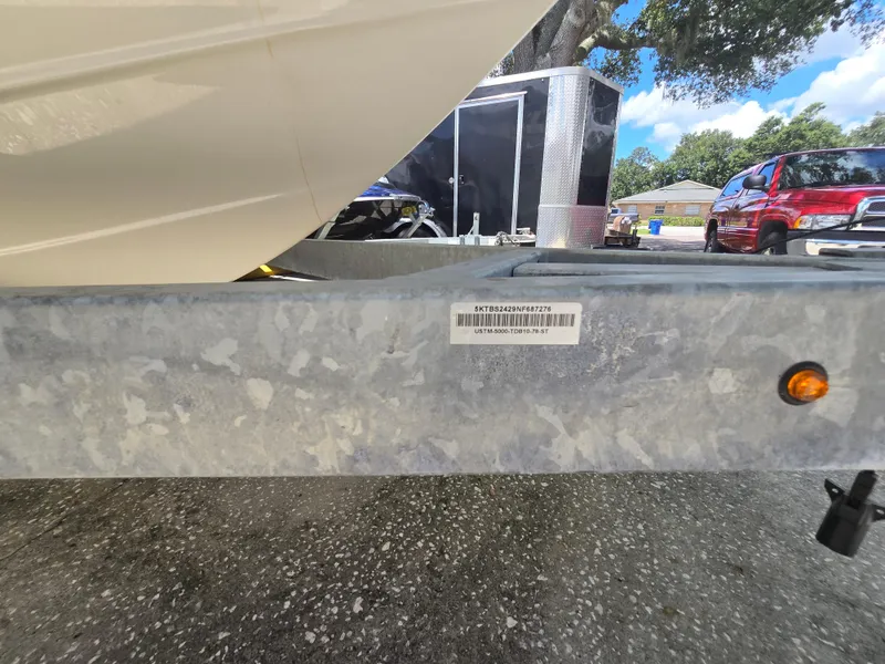 Slide: The Image of 2022 Bayliner Trophy T20CC boat trailer with VIN label, parked outdoors. - 18