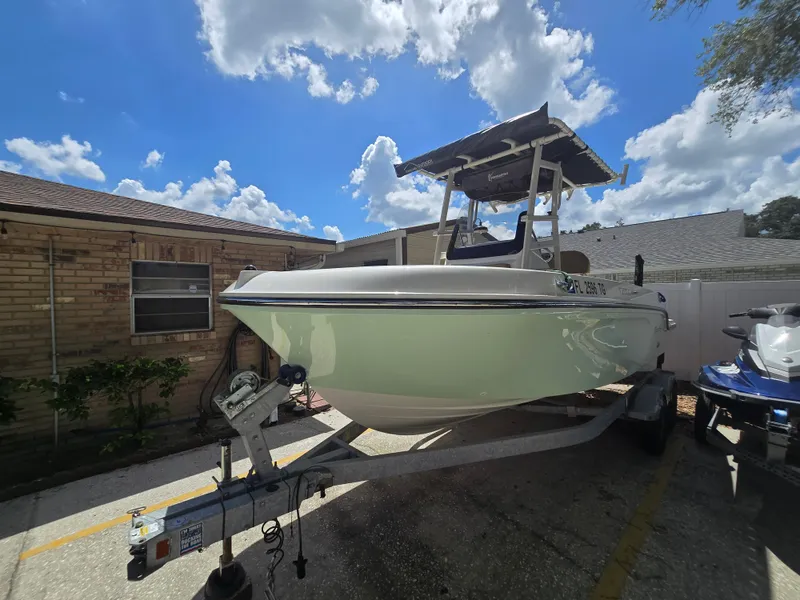 Slide: The Image of 2022 Bayliner Trophy T20CC boat on trailer, parked beside a house under a blue sky. - 2