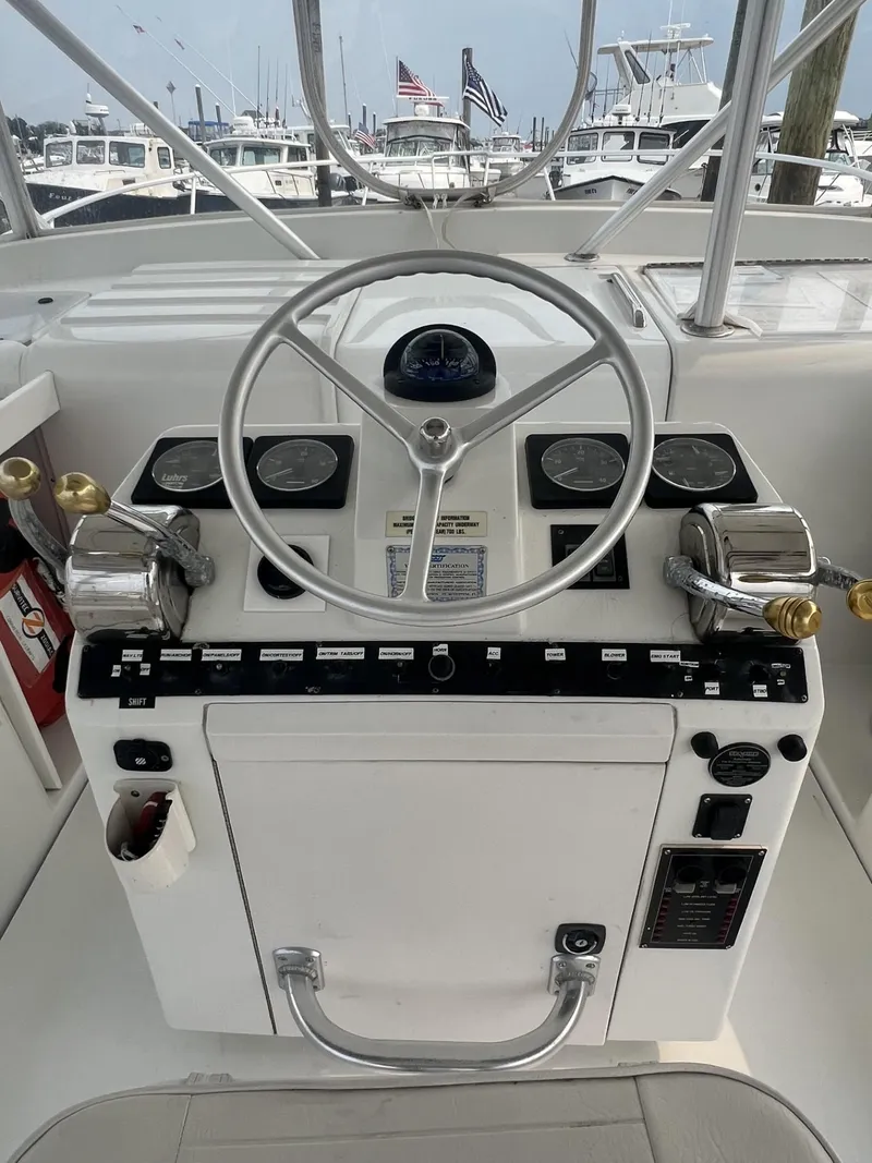 Slide: The Image of 1995 Luhrs 320 Open helm with steering wheel and control panel, docked in a marina. - 11