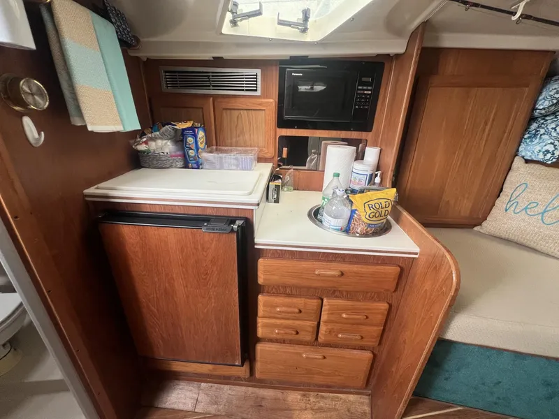 Slide: The Image of 1995 Luhrs 320 Open cabin kitchen with wooden cabinets, mini-fridge, and microwave. - 17