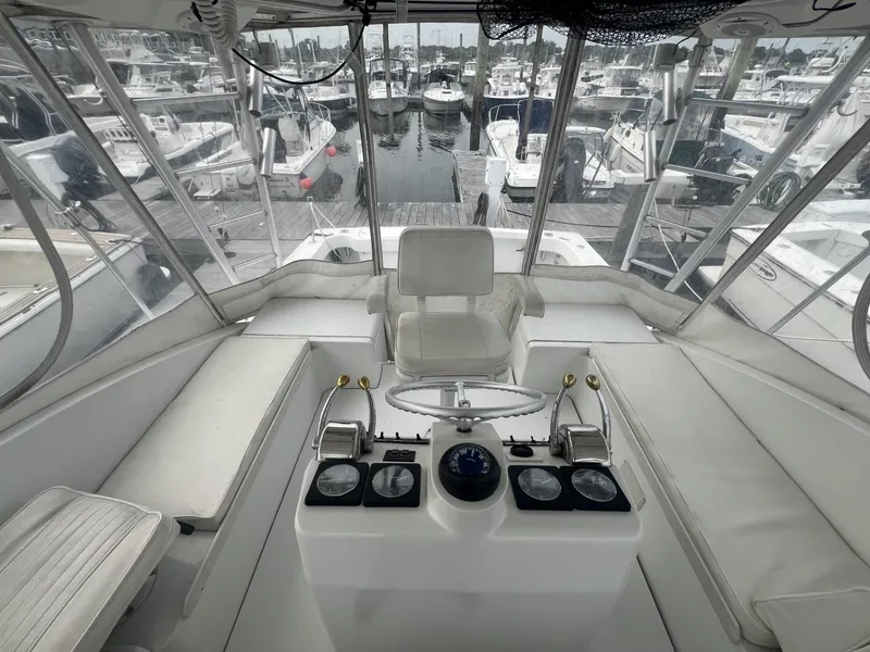 Slide: The Image of 1995 Luhrs 320 Open boat helm with marina view, featuring white seating and control panel. - 9