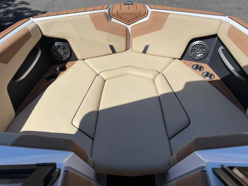 Slide: The Image of 2025 Nautique Super Air Nautique GS22 boat interior with beige seating and cup holders. - 11