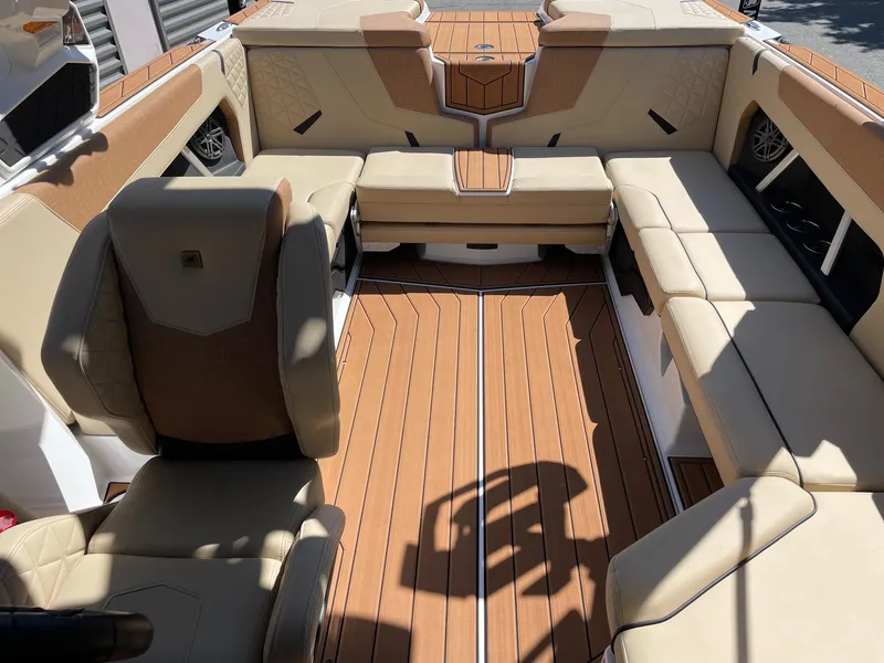 Slide: The Image of 2025 Nautique Super Air Nautique GS22 interior with beige seating and wood flooring. - 12