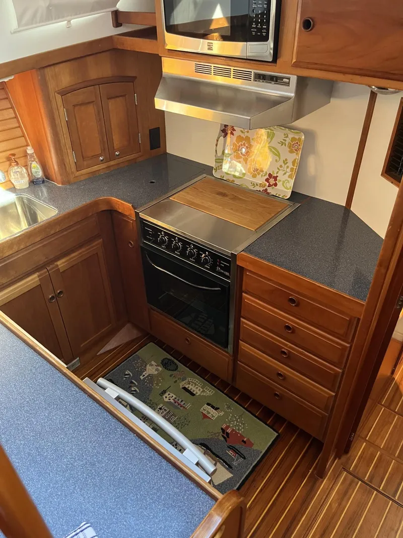 Slide: The Image of 1999 Sabre Sabreline 47 yacht kitchen with wooden cabinetry and modern appliances. - 12