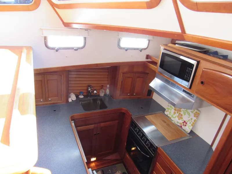 Slide: The Image of 1999 Sabreline 47 yacht kitchen with wood cabinetry, microwave, and stove. - 13