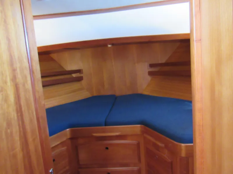 Slide: The Image of 1999 Sabre Sabreline 47 yacht cabin with wooden interior and blue cushions. - 22