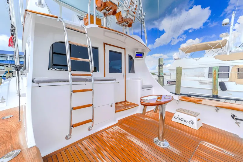 Slide: The Image of 1982 Hatteras 46 Convertible yacht with wooden deck and ladder, docked under blue sky. - 35