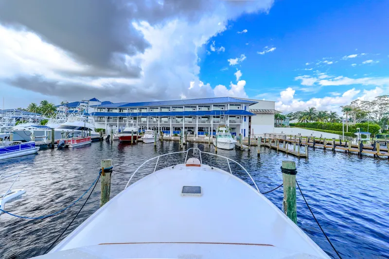 Slide: The Image of 1982 Hatteras 46 Convertible docked at a marina under a partly cloudy sky. - 46
