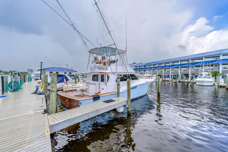 Slide: The Image of 1982 Hatteras 46 Convertible yacht docked at marina under cloudy sky. - 47