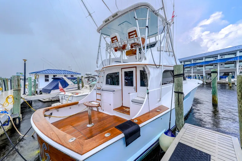 Slide: The Image of 1982 Hatteras 46 Convertible yacht docked at marina, featuring spacious deck and flybridge. - 48