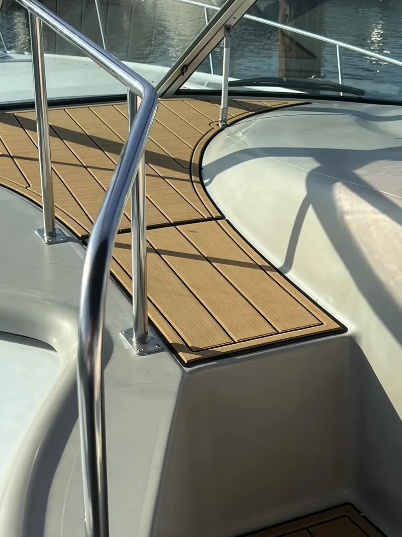 Slide: The Image of 2004 Cruisers Yachts 320 Express deck with sleek railing and wood finish. - 16
