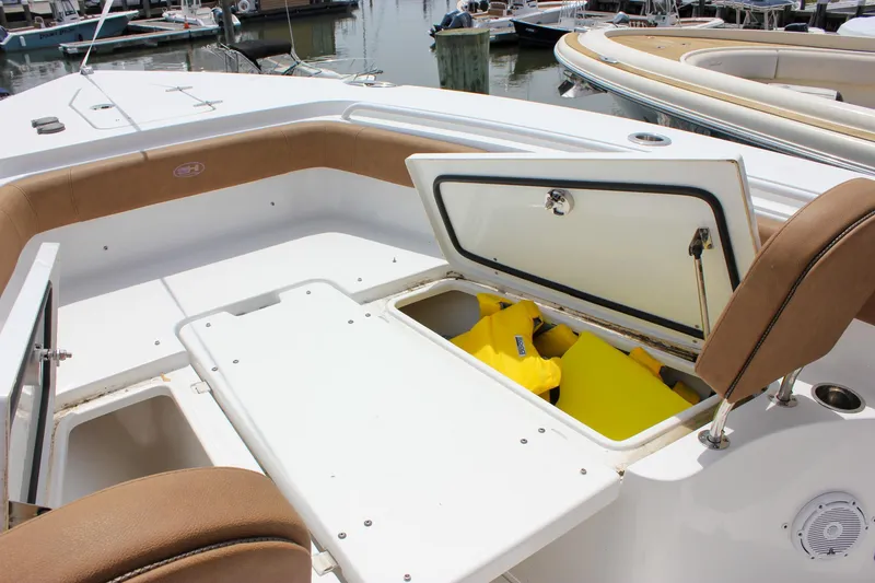 Slide: The Image of 2022 Sea Hunt Gamefish 27 Forward Seating with open storage compartment and yellow life jackets. - 16