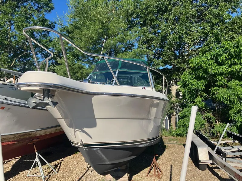 Slide: The Image of 1998 Pursuit 2860 Denali boat on dry dock, surrounded by trees and other boats. - 0