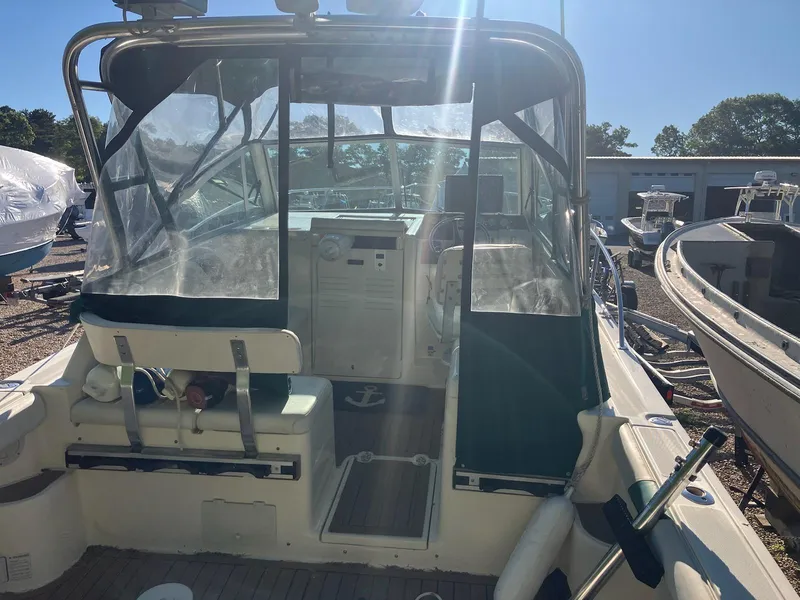 Slide: The Image of 1998 Pursuit 2860 Denali boat with clear canopy and seating, docked under sunlight. - 1
