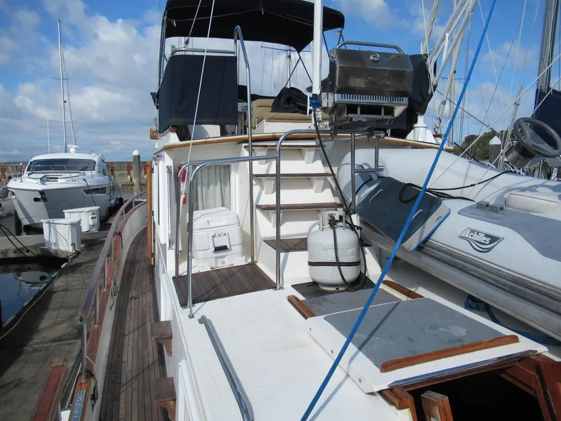 Slide: The Image of 1985 Grand Banks 42 Classic yacht docked, featuring upper deck and dinghy. - 26
