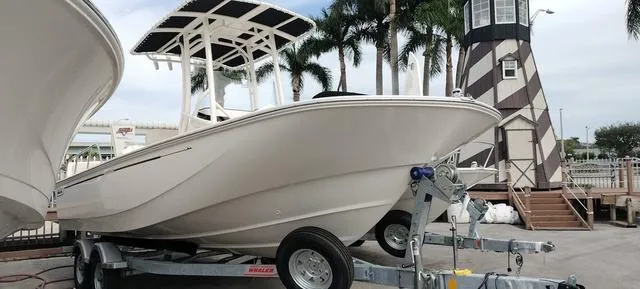 Slide: The Image of 2024 Boston Whaler 210 Montauk boat on trailer near lighthouse and palm trees. - 18