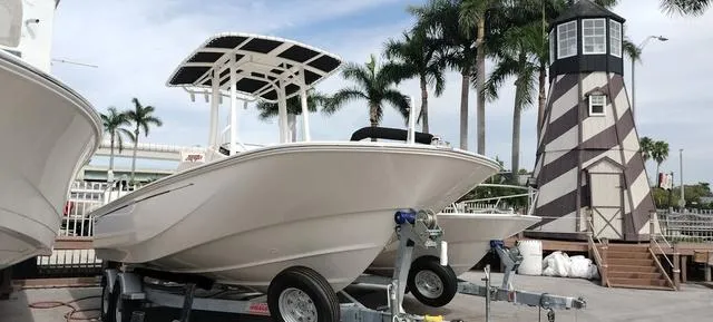 Slide: The Image of 2024 Boston Whaler 210 Montauk boat on trailer near lighthouse and palm trees. - 20