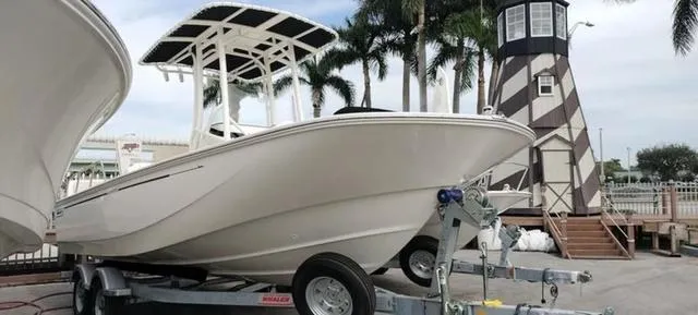 Slide: The Image of 2024 Boston Whaler 210 Montauk boat on trailer near lighthouse and palm trees. - 3