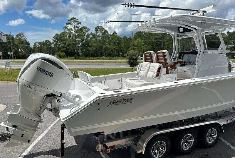 Slide: The Image of 2025 Jupiter 32 boat with Yamaha engine on a trailer, parked outdoors. - 49