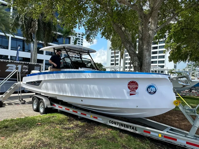 Slide: The Image of 2025 STERK 31 WB Sport boat on trailer, displayed outdoors under trees. - 11
